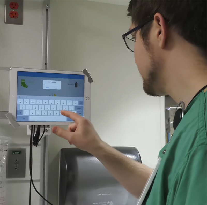 Nurse filling out field on tablet completing electronic rounding